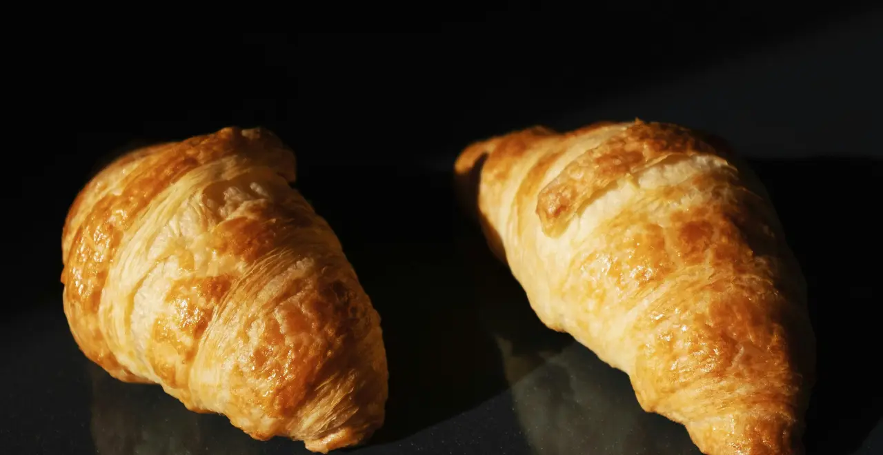 Chef préparant des croissants au jambon, étalant la garniture sur la pâte